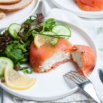 A smoked salmon appetizer shown on a plate next to a salad.