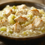 A photo showing a chicken risotto recipe in a bowl on a wooden table.