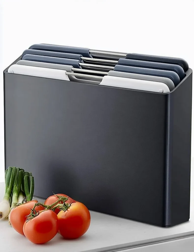 An image showing Joseph Joseph colour coded chopping boards on a kitchen counter top with tomatoes and onions