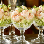 A photo showing a typical prawn cocktail recipe with 3 prawn cocktails shown in glasses with lettuce.