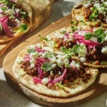 A photo showing lamb flatbreads on a chopping board that looks like they have just been dished up and ready to eat.